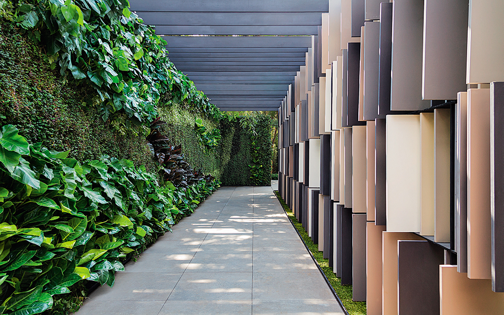 Alex Hanazaki brinda os visitantes com uma entrada linda. Brises de pisos da Eliane sustentados por estrutura metálica e um jardim vertical incrível.