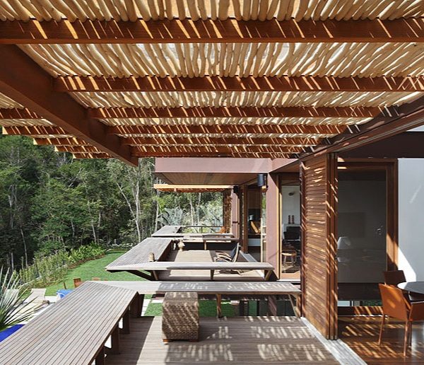 Pergolado que combina estrutura em madeira e tronquinhos irregulares, de Miguel Pinto Guimarães.