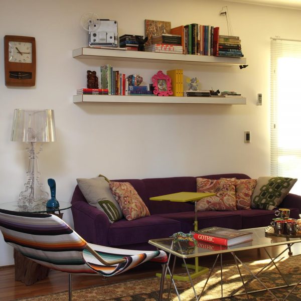 Em pequenos ambientes, todos os espaços  tem que ser considerados. As prateleiras sobre o sofá organizam objetos e livros.