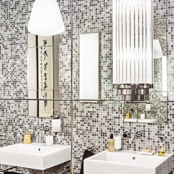 O banheiro repaginado evoca os anos 1930. Arandela art decó e revestimento Bisazza.