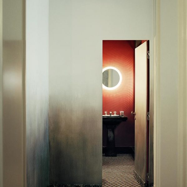 A porta invisível recebeu o mesmo tratamento das paredes, tinta prateada. O lavabo é vermelho intenso.