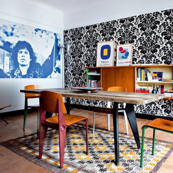 O tecido P&B na parede movimenta o jantar, que recebe foto dos Rolling Stones, mesa com tampo em mármore e cadeiras Jean Prouvé sobre tapete dinamarquês