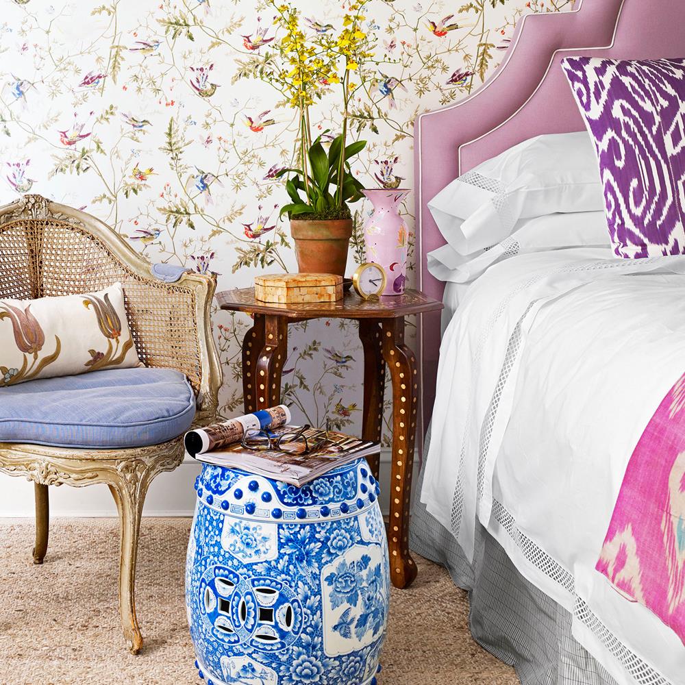 No quarto, cabeceira lilás, garden seat azul e mesa lateral em madeira marchetada.