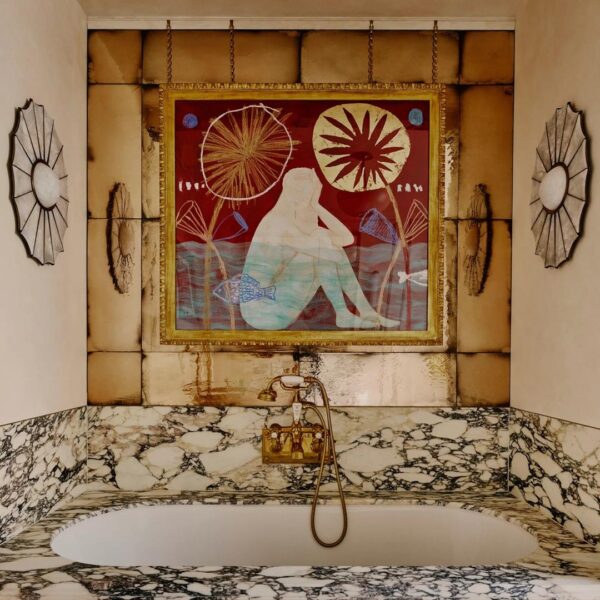 Um espelho antigo de Rupert Bevan e obras de arte de Delia Harmer, acima da banheira.